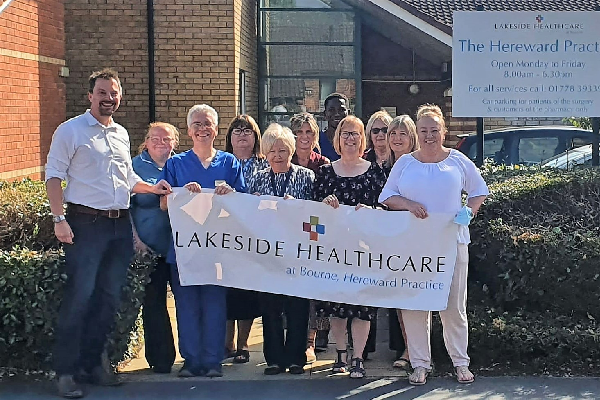 Practice staff standing outside the practice with a Lakeside Healthcare banner